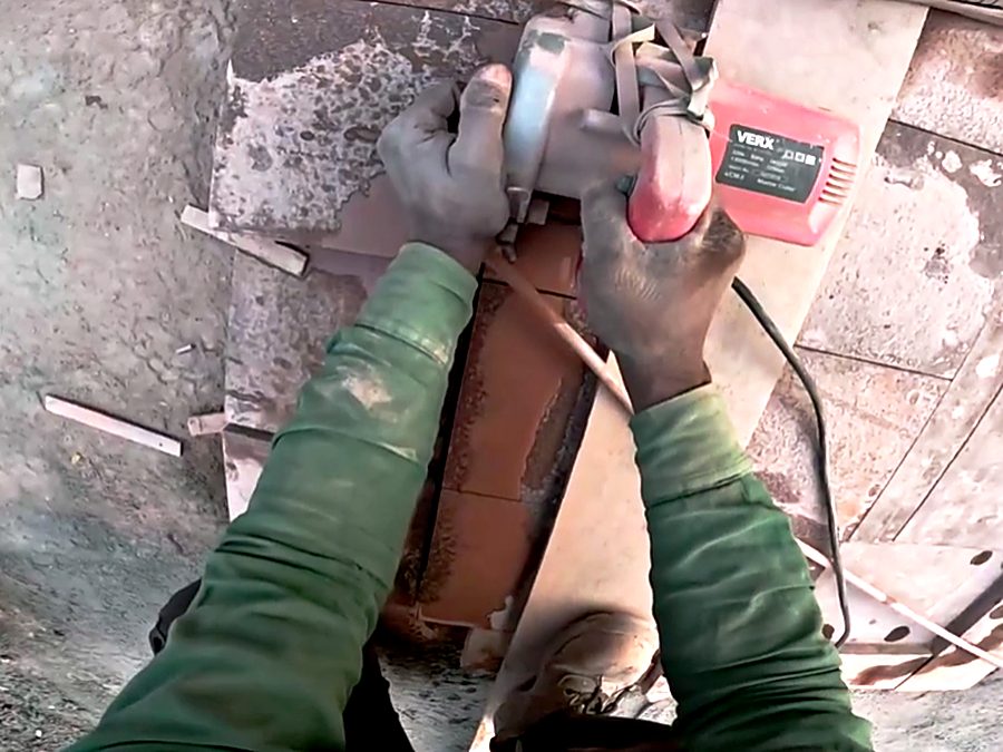 Both hands guiding an angle grinder across a block on a building site.