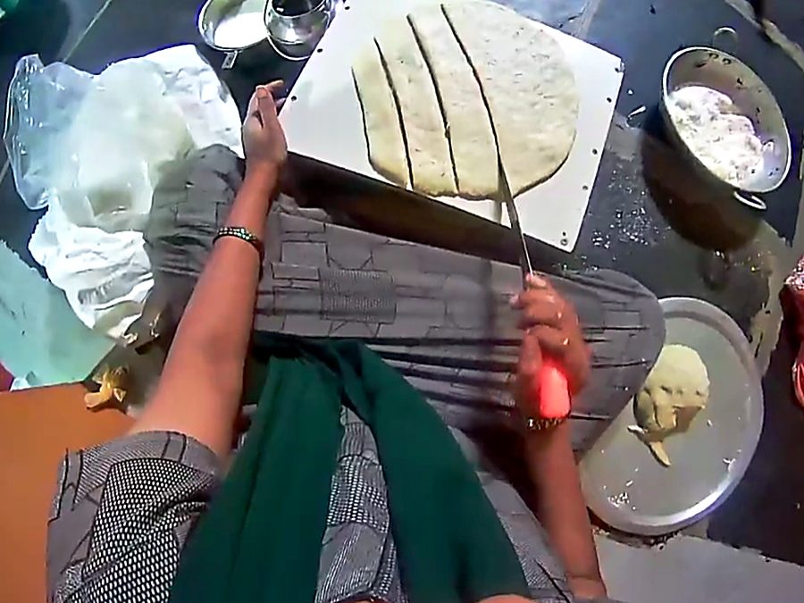 Rolling and cutting dough on a board, both hands in frame.