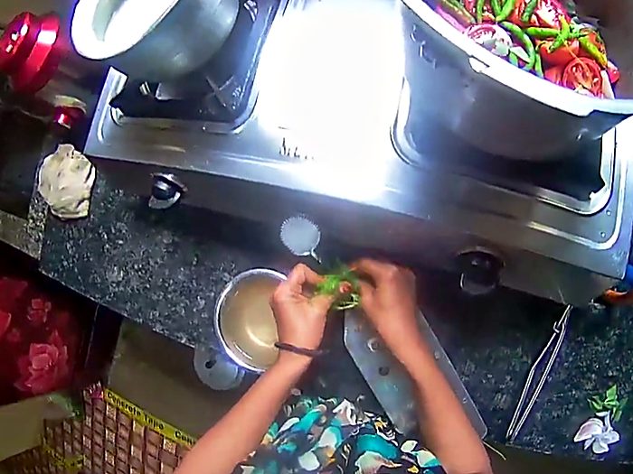Cooking at a stove, stirring a pan of vegetables.