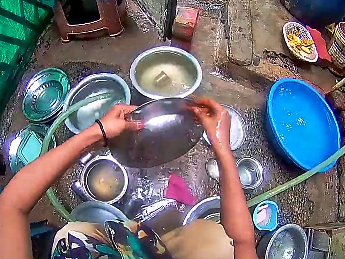 Rinsing utensils at an outdoor washing area.