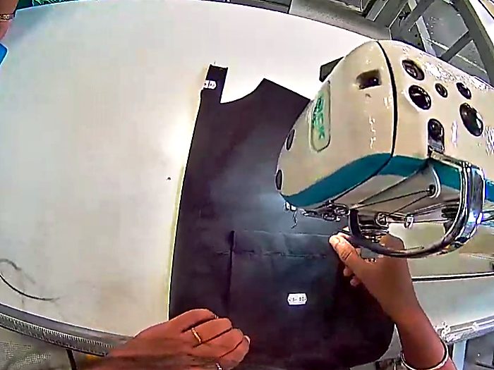 Feeding fabric under the needle of an industrial sewing machine.